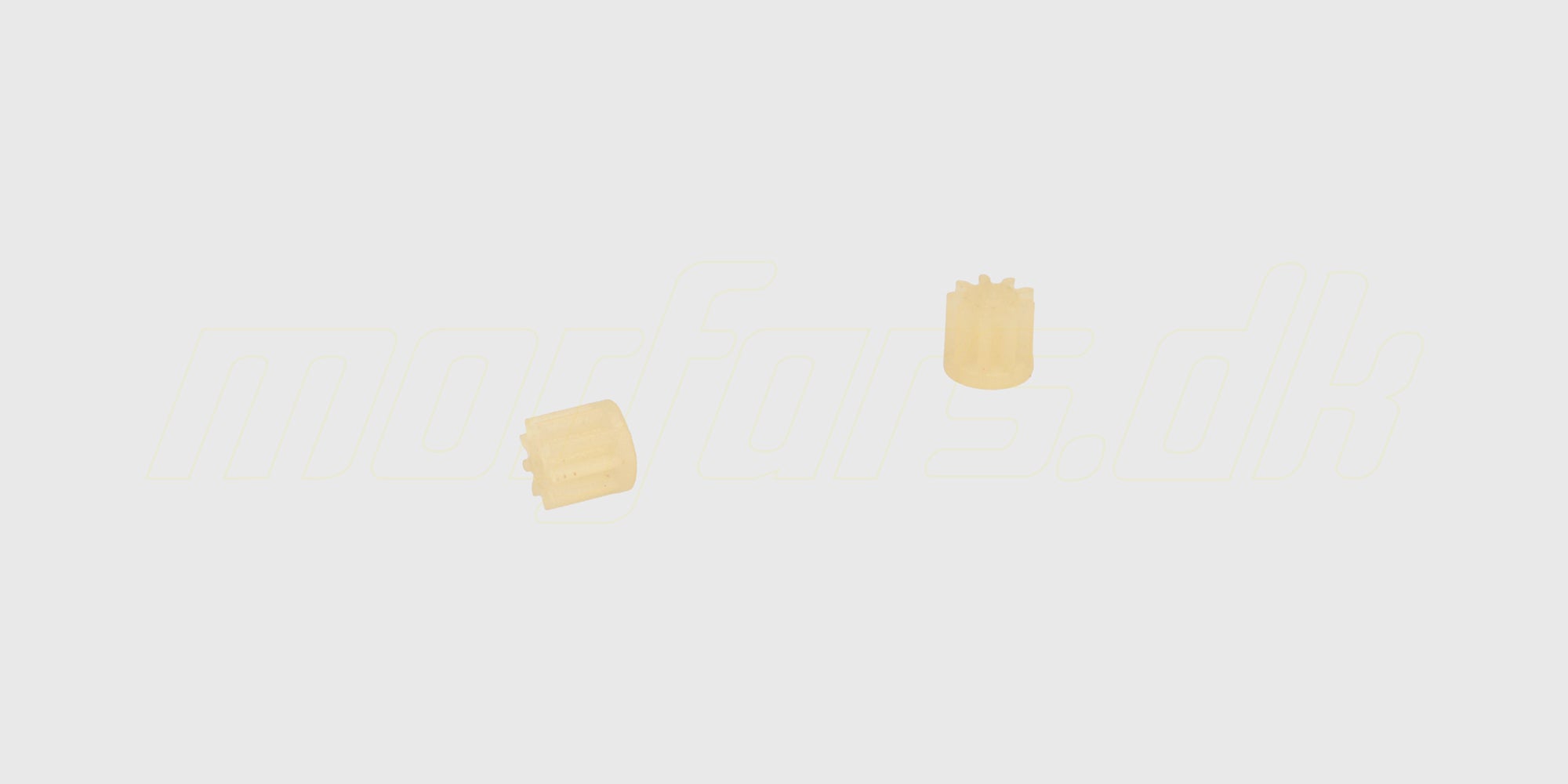 To hvide tandhjul i plast til motoren på en FireFox C129 fjernstyret helikopter vist på hvid baggrund.