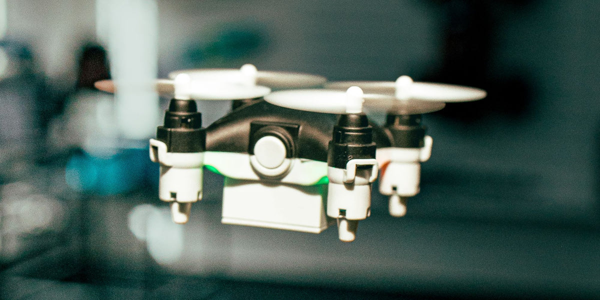Sort Micro Drone i luften tæt på med grønt lys i undersiden